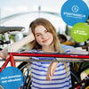 Zu sehen ist eine Frau, die sich auf ein Fahrrad stützt