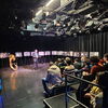 Zu sehen ist die Ausstellungseröffnung mit den Bildern der Fotoaktion auf Staffeleien in einem Theatersaal.