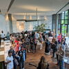 Zu sehen sind Menschen im Foyer eines Restaurants, die gemeinsam singen und tanzen.